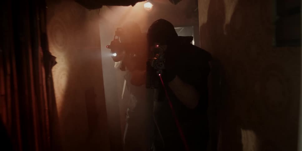 Police slowly walk through a dark hall with guns drawn