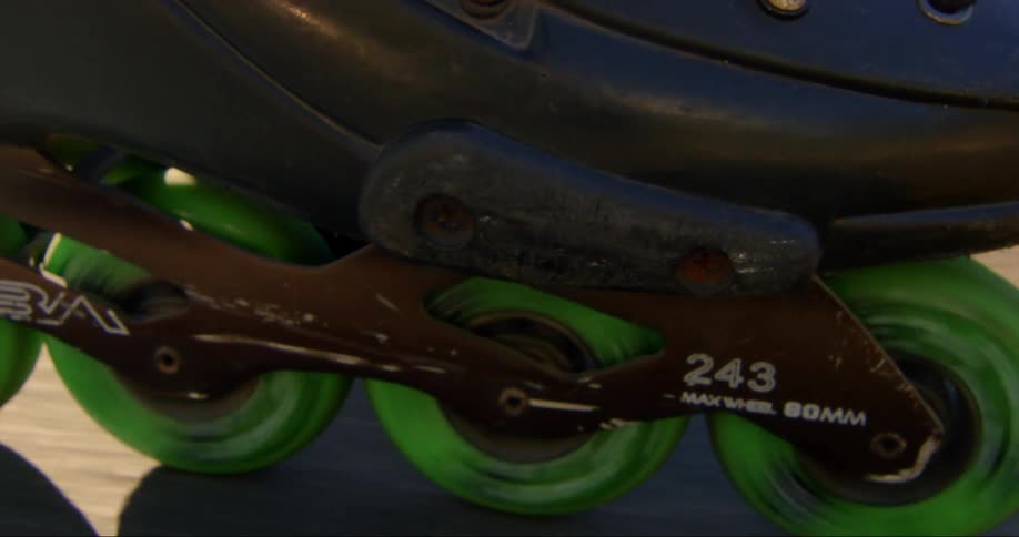 The green wheels of roller blades spin as they move across the road