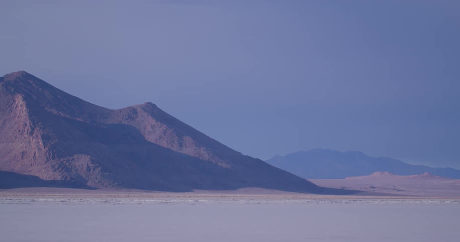 Ice and snow stretch to plain bordering mountains on foggy day