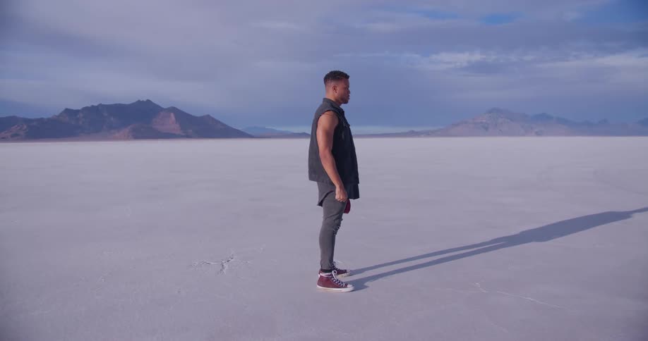 Young man stands still on the flat plains of a desert at daytime