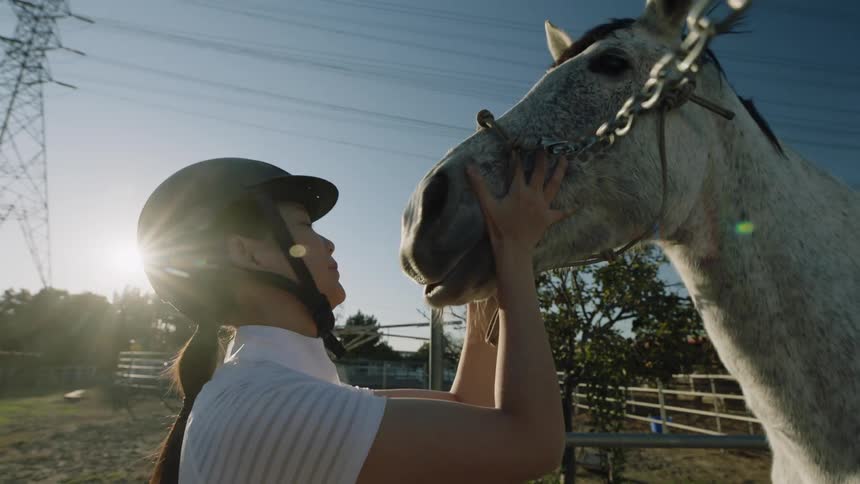 Close up of a female jockey holding the head of a horse at morning