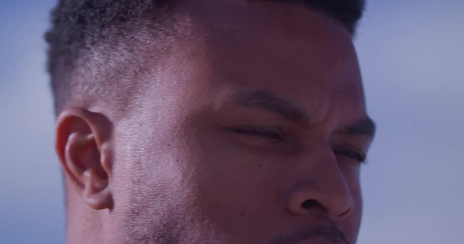 Under cloudy sky man stares while clenching his jaw