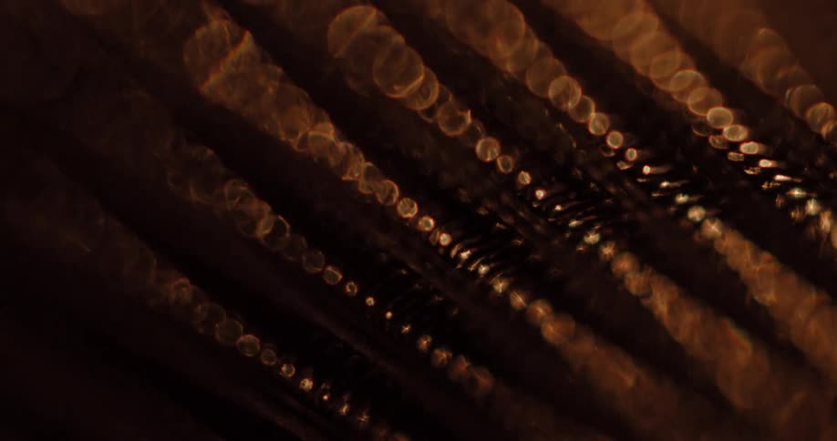 Light brightens rib patterned metal surface creating a glare before it fade to darkness