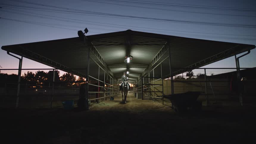 Woman rides out of open air barnbuilt near power lines at night