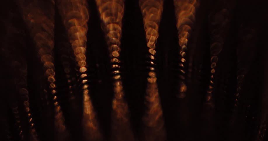 Light shines on textured ribbed surface creating shadowed crevices and a shimmering glare