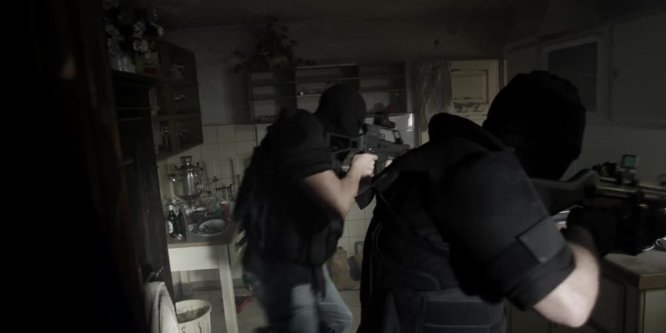 Armed men move through a kitchen