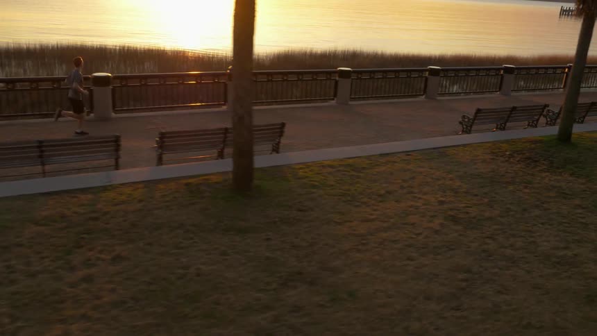 A man is running on the boardwalk at sunset