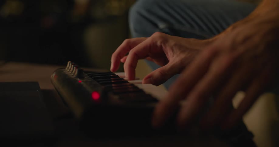 Someone is sitting down playing a small electronic keyboard with both hands