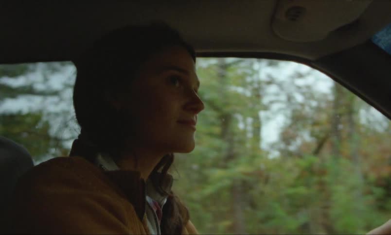 Woman in brown jacket drives car in the countryside