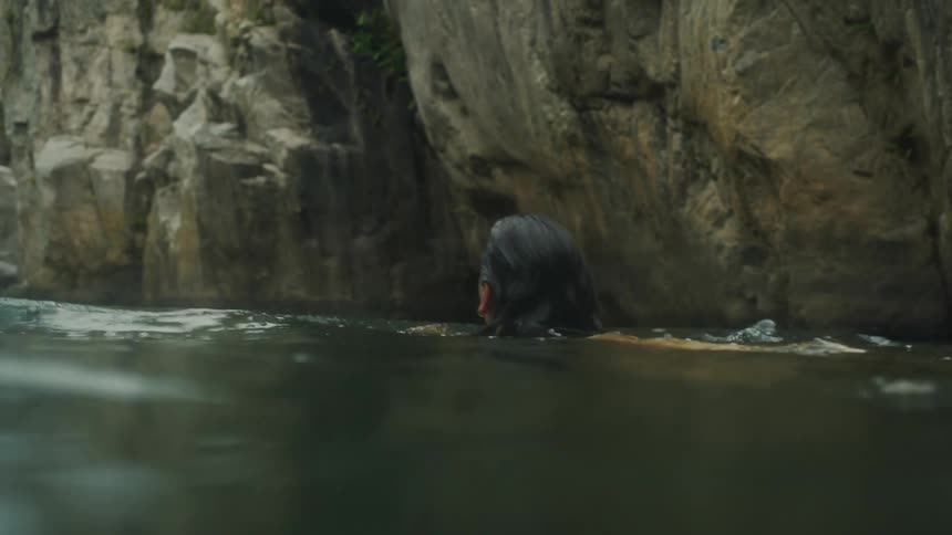 A younger white woman is swimming outside in the lake