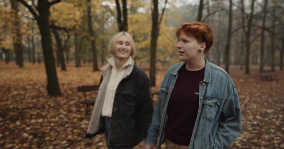 Two women are walking through a forest during autumn