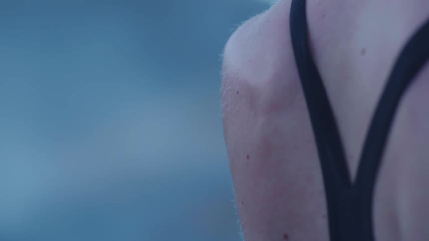Wet back of a woman wearing a black swimsuit outdoors a morning