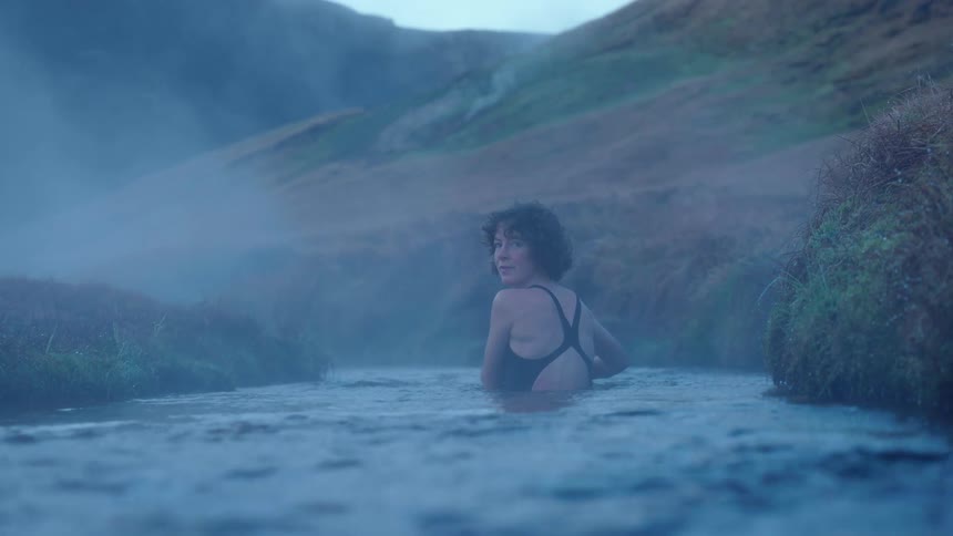 A young woman is swimming in the late in the middle of the day