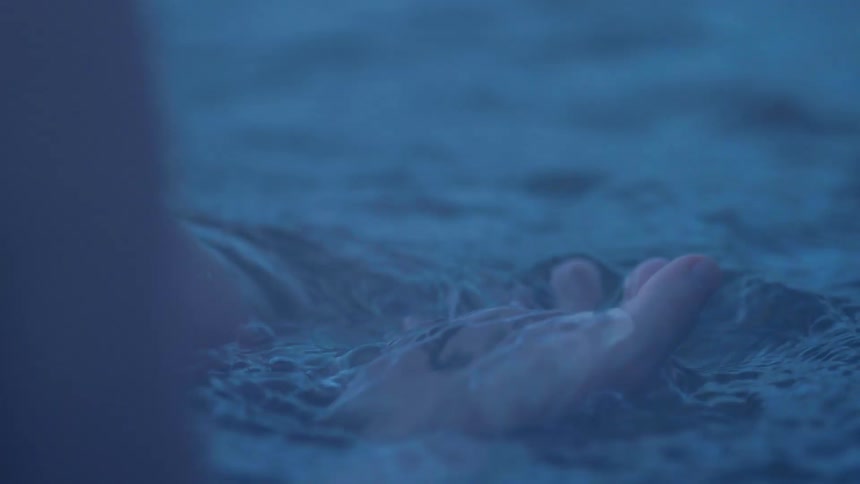 A person lets flowing river water pass through their fingers while calmly turning their hand over