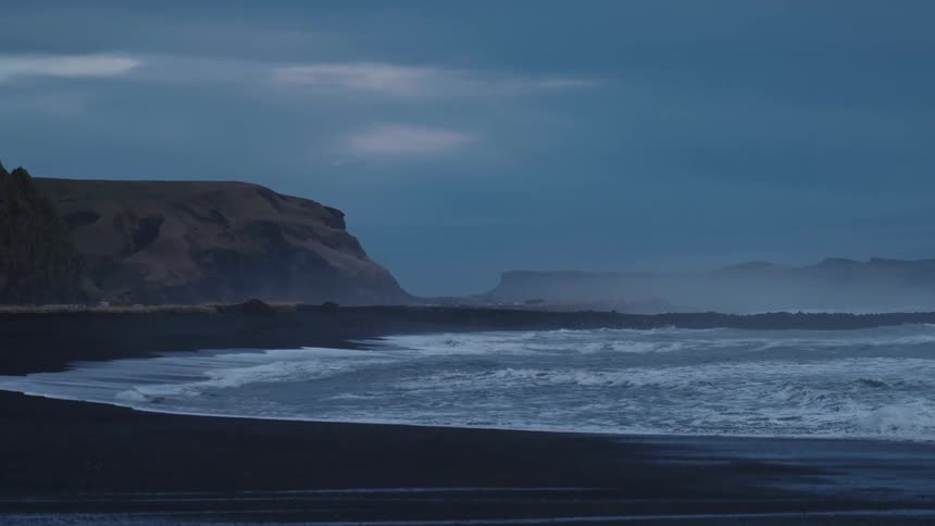 Landscape of wavy ocean and black sand beach
