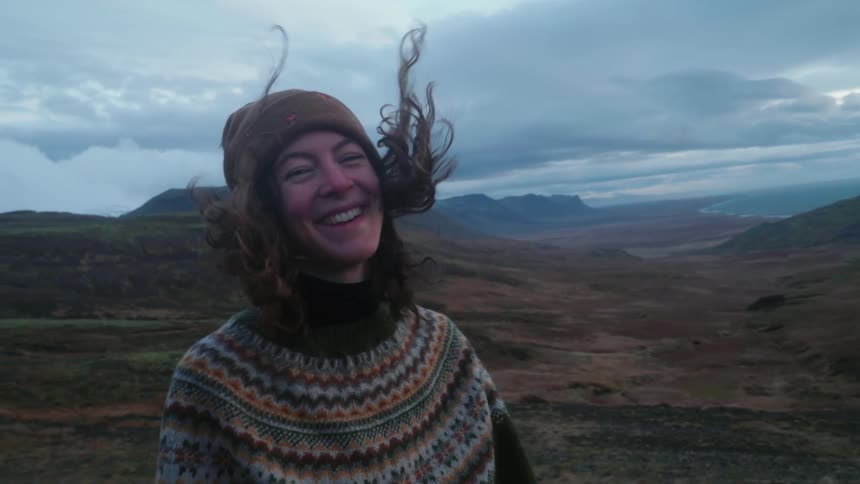 A woman is smiling outdoors in a wilderness area