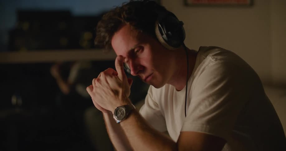 A man is putting on his headphones and sitting down