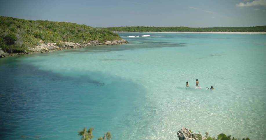 Friends swimming in clear blue water in a cove at a tropical location