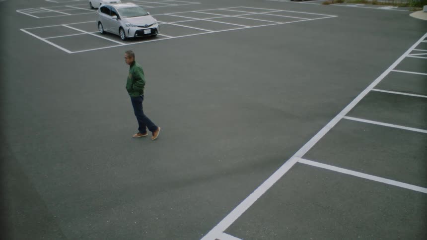A man paces back and forth in a parking lot during the day