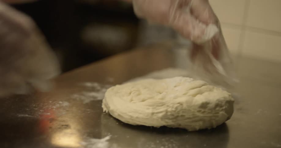 Man kneads dough on counter in the kitchen