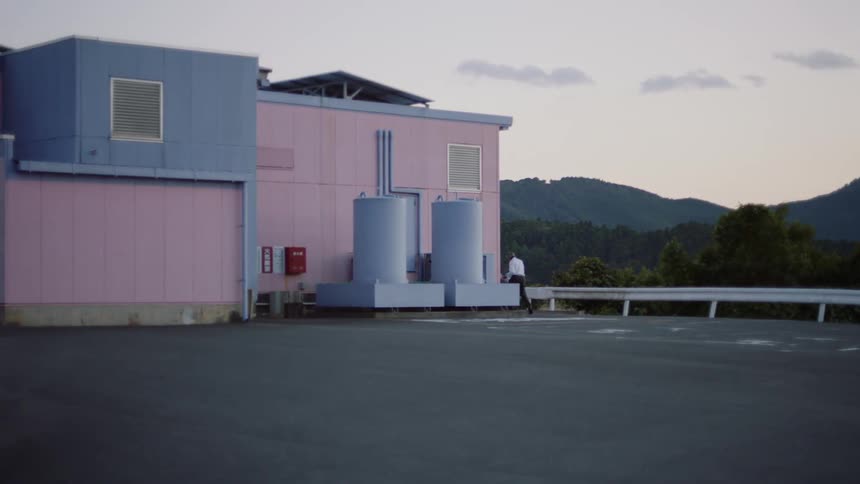 A man is walking behind a building during the spring time