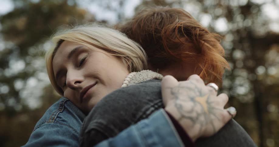 A young couple is hugging each other outside in the day time