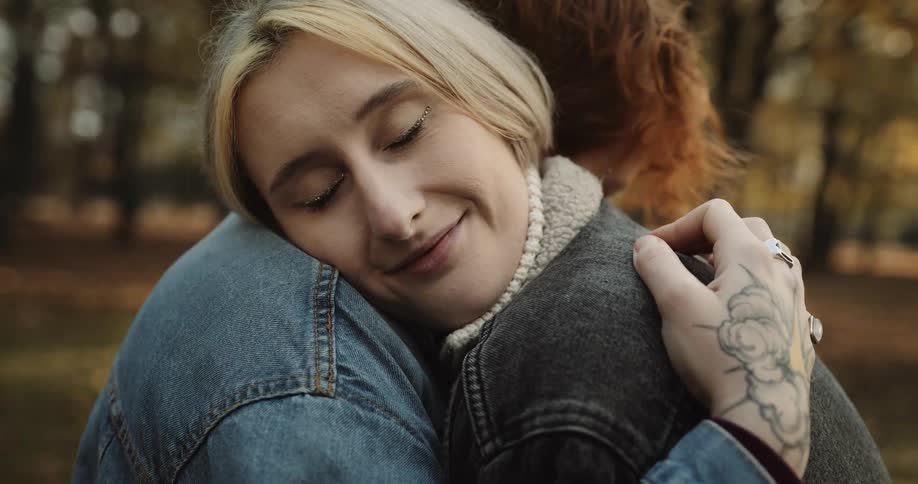 Two people are hugging each other outdoors during autumn