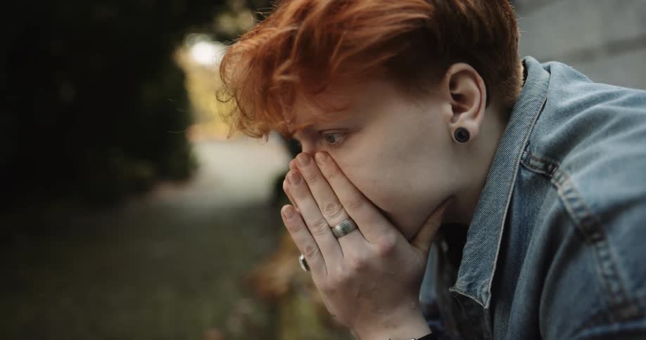 Close up of the face of a young woman patiently waiting while sitting on a park bench