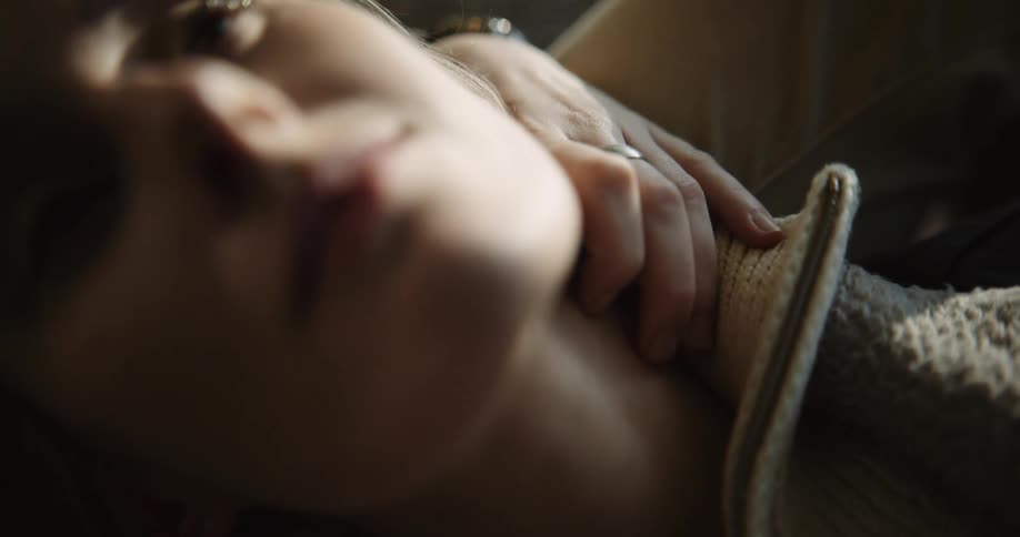 A young blonde woman is laying down inside of her home
