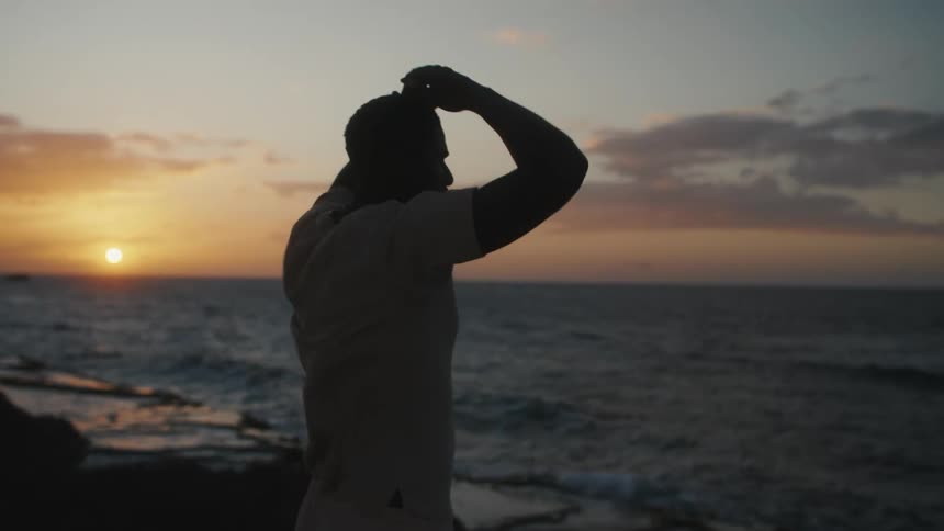 Man walking out and admiring coastline at sunrise