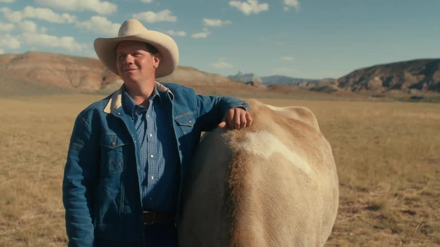 A young cowboy is hanging out on a ranch with a horse