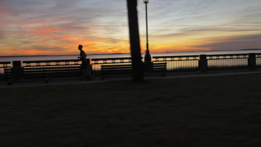 A man is running along the boardwalk near the shore