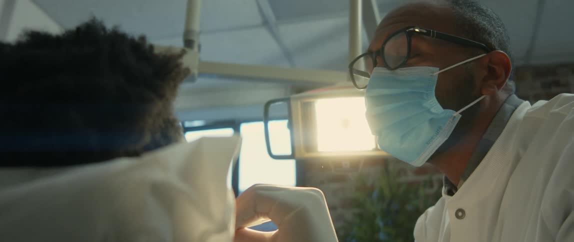 Dentist wears face mask while he examines patients teeth