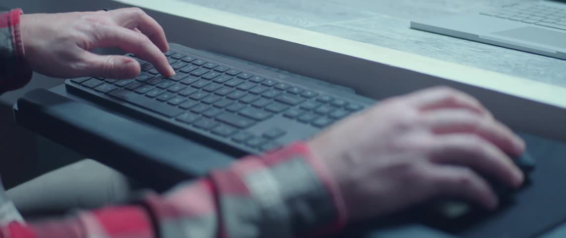 A man moves a mouse and uses a keyboard