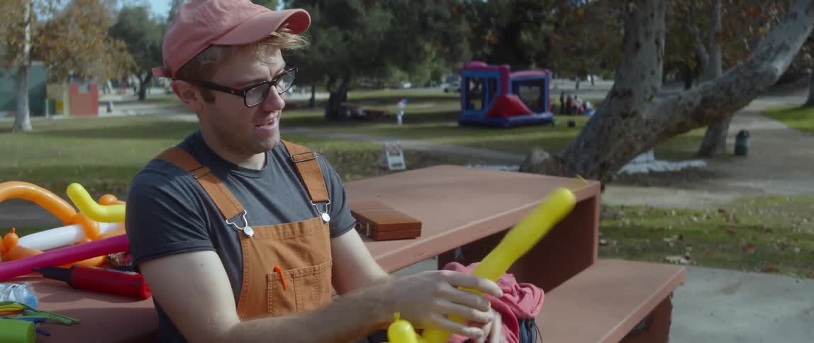 A man is making balloons at a park during spring