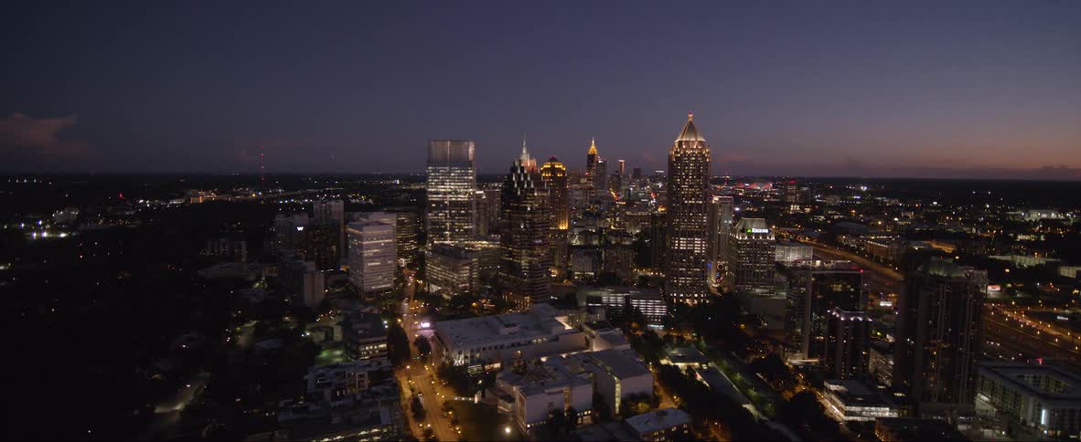Skyscrapers are lit up at night in a bustling city