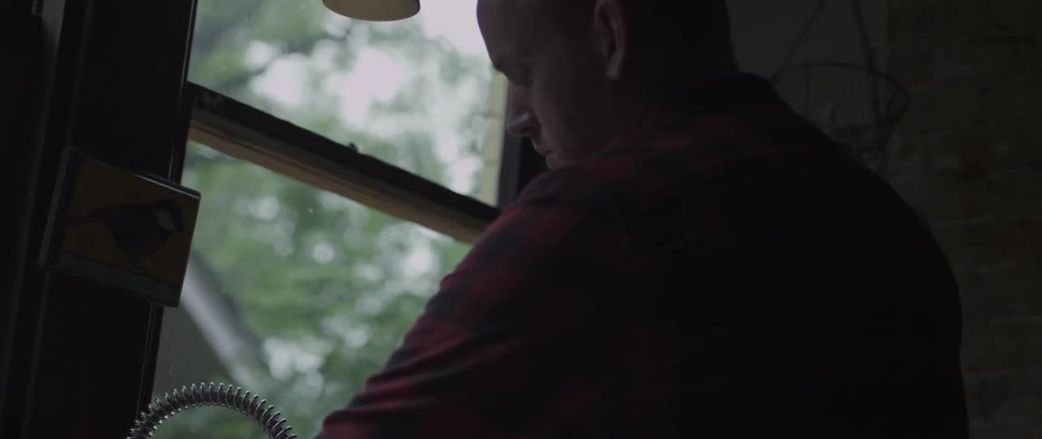 A man walks over to a window on a rainy day
