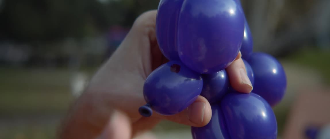 Someone is using a marker to draw on an animal twisted from a blue balloon