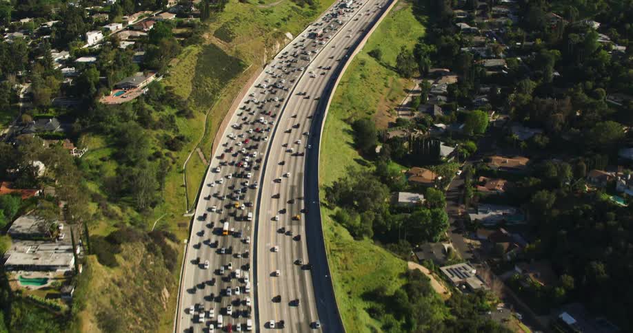 Heavy traffic passes down a freeway running through a suburb