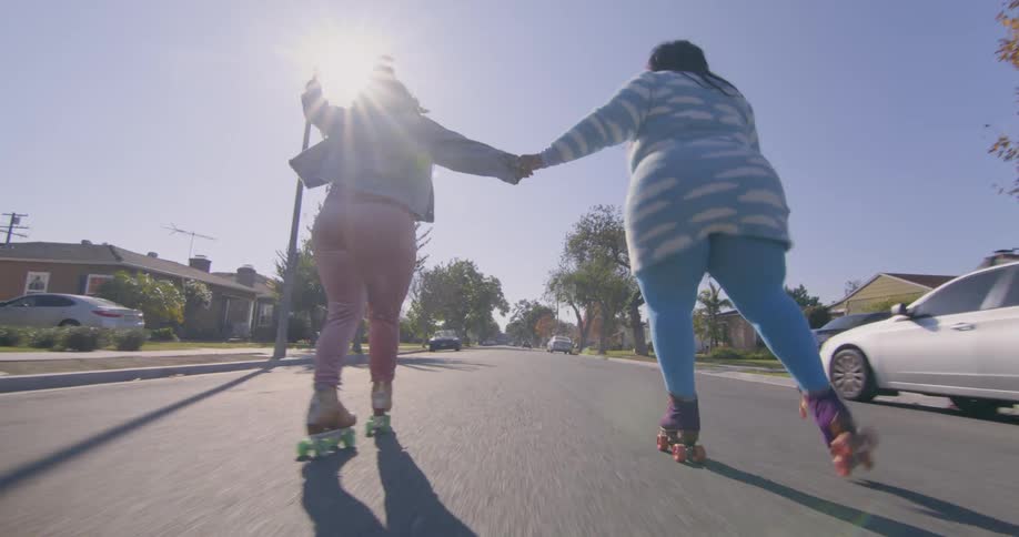 Mother and daughter skating on the neighbrohood streets at morning