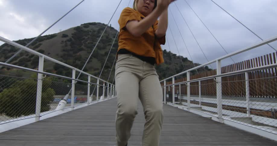 A female is dancing on a bridge by herself