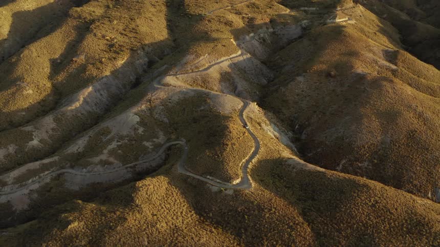 Aerial view of car driving on winding road on desert hills