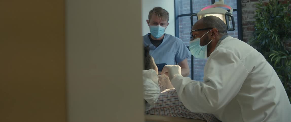 Dentist examines patients teeth while tech enters data on tablet
