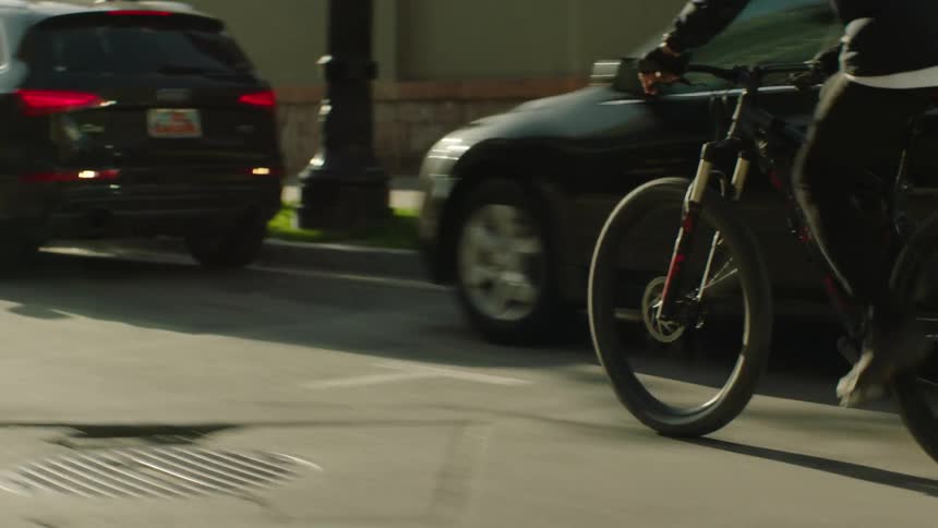 Man rides mountain bike down the street near parked cars