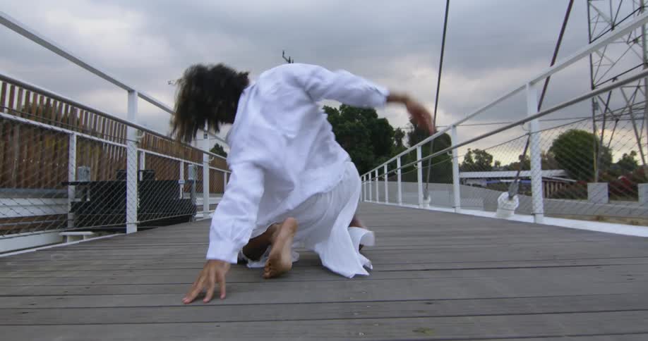 A man dancing and crawling outdoors