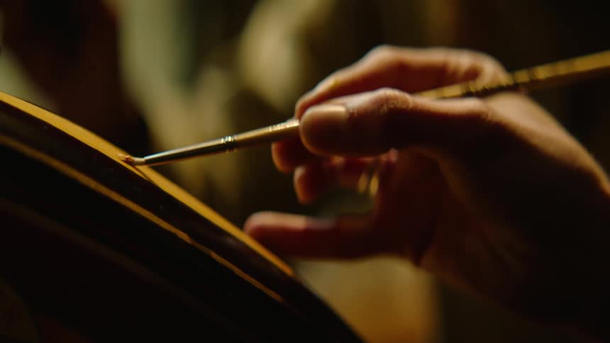 Artist applies paint to object with a small brush