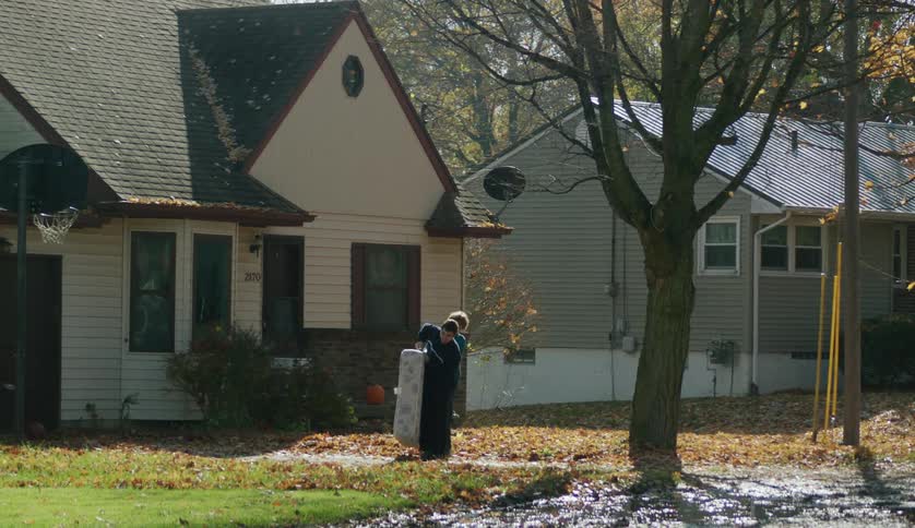 Two children carry a bed in the yard