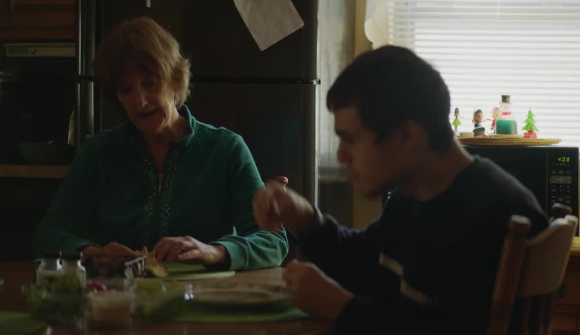 Grandmother and grandson eating lunch in the kitchen at home