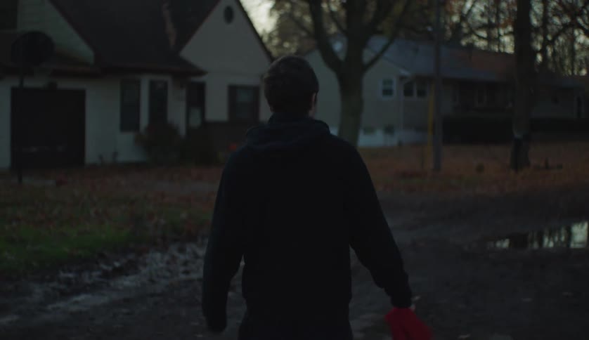 A young teenage boy is walking outside in the middle of the day
