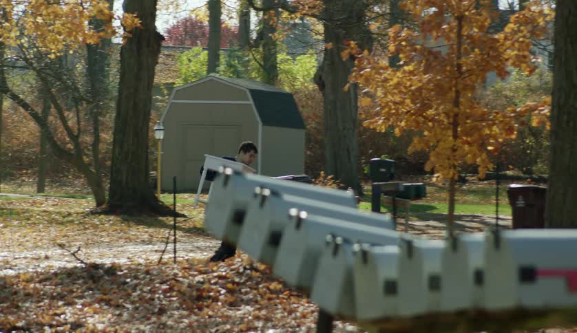 A young man is carrying a table outside in the middle of the day